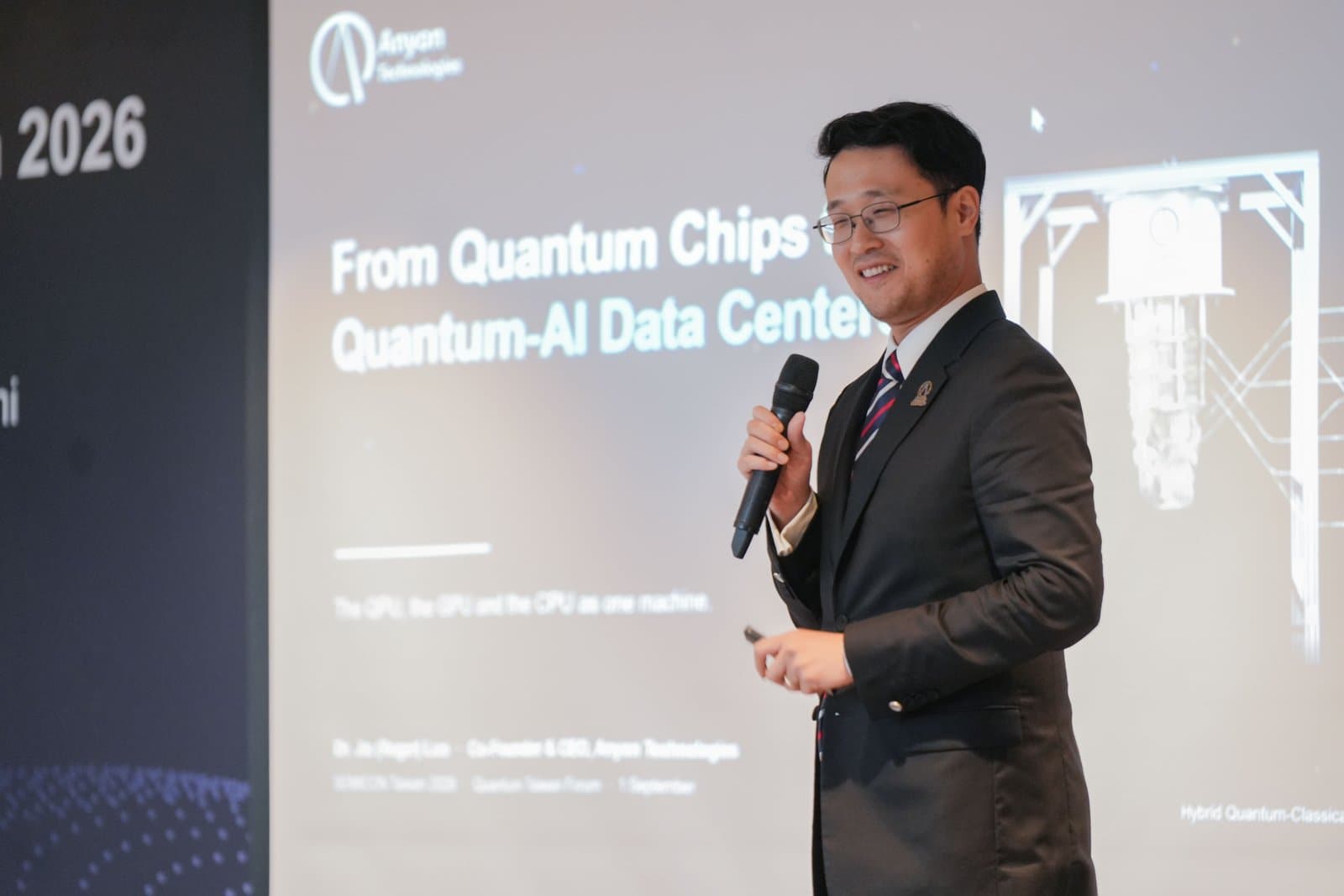 Roger Luo speaking at the Quantum Taiwan Forum at SEMICON Taiwan 2026, in front of a slide titled From Quantum Chips to Quantum-AI Data Centers.